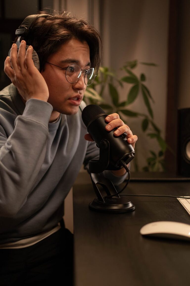 man sitting at the table wearing headphones and talking to the microphone