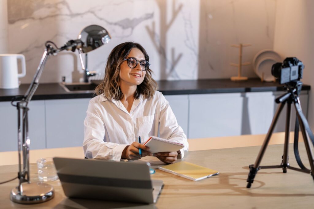 woman in white long sleeve shirt wearing black framed eyeglasses holding white notepad