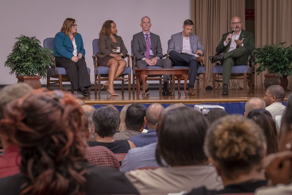 Panel de expertos participando en una conferencia o foro académico ante una audiencia, discutiendo temas profesionales relevantes para la gestión administrativa.