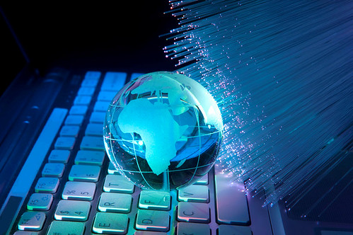 Globo terráqueo de cristal sobre un teclado de ordenador iluminado por fibras ópticas azules